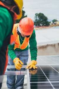 مهندس طاقة شمسية يتفقد تركيب الألواح في موقع بناء مستدام، حيث يلتقي الابتكار البيئي بالهندسة الحديثة.