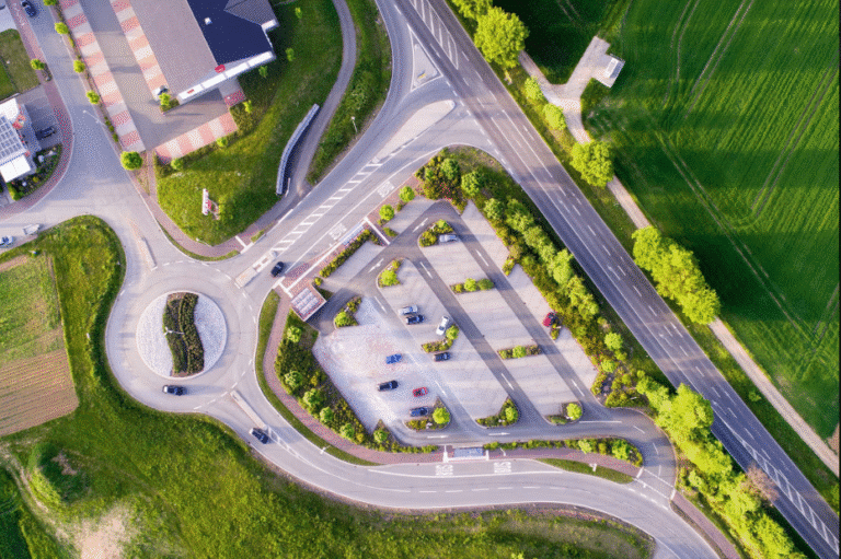 Aerial view of a well-organized urban intersection with clearly defined roads, neatly arranged parking areas, and surrounding green spaces enhancing the city layout.