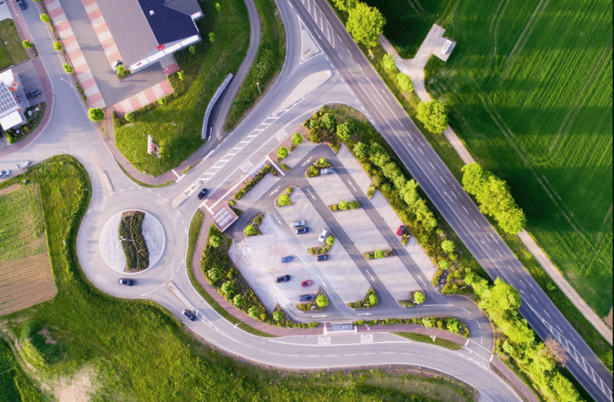 Aerial view of a well-organized urban intersection with clearly defined roads, neatly arranged parking areas, and surrounding green spaces enhancing the city layout.