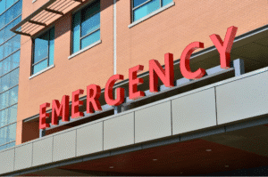 A hospital building with a large red sign displaying the word 'EMERGENCY,' indicating the entrance to the emergency department.