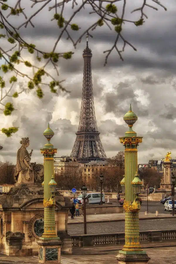 The iconic Eiffel Tower stands majestically in the heart of Paris, surrounded by ornate columns and lush green trees.