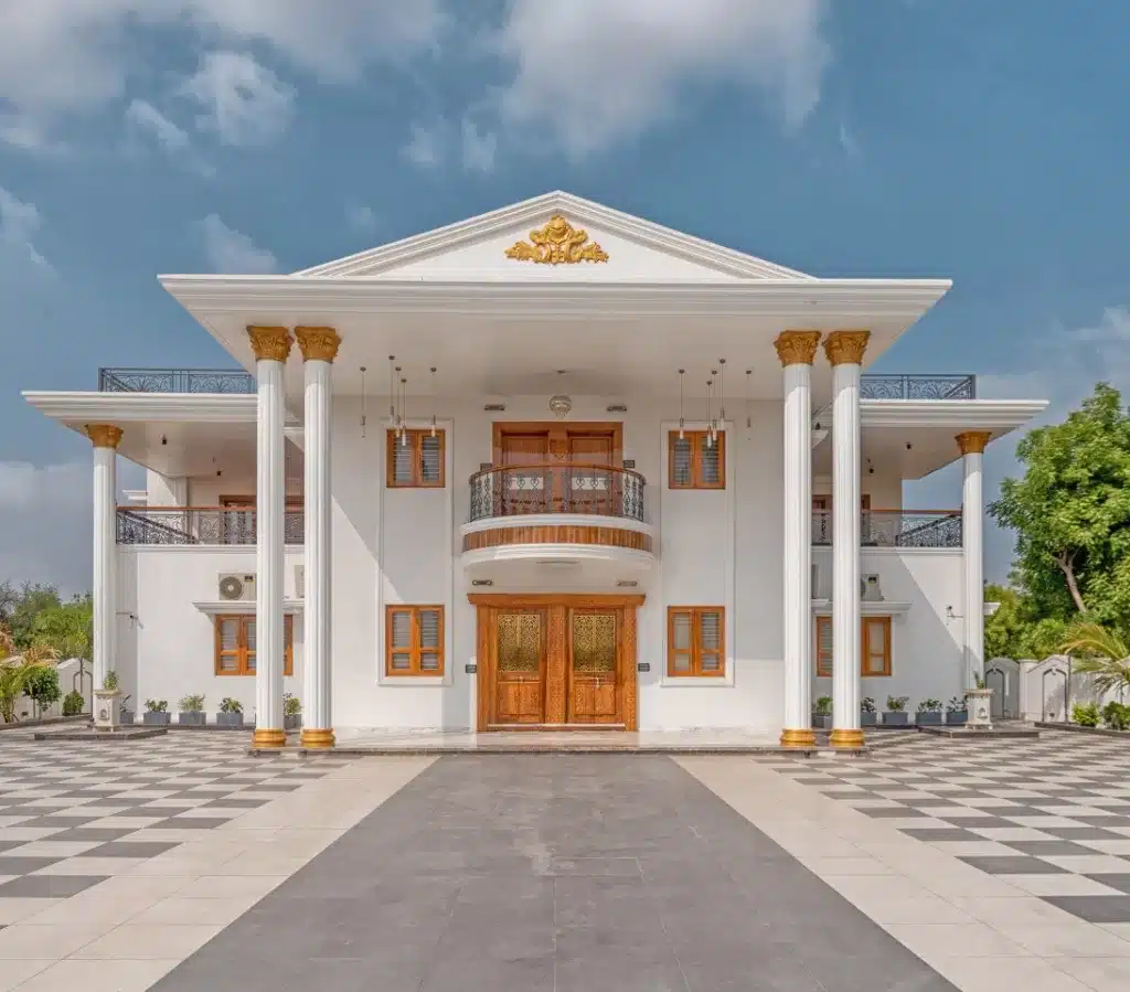 A modern white building featuring classical white columns with golden bases, a central wooden door, and glass latticework windows.