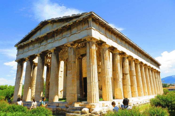 An ancient temple with massive Doric columns and ornate pediments under a clear sky.