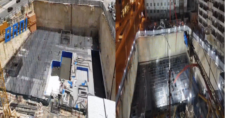 Construction is steadily progressing at the Al-Rassais Residential Tower site, with visible progress in foundation and structural work. Large-scale equipment, including red cranes branded with 'BAM,' is actively in use. Workers are fully equipped with safety vests and harnesses, and the site is well-organized with clear pathways for movement.