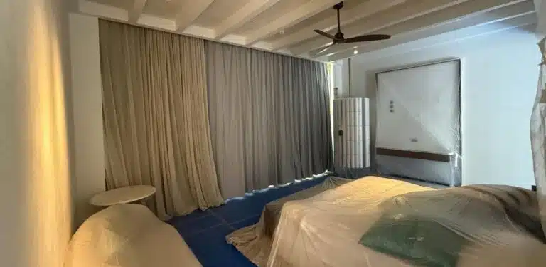 A bedroom under construction in one of the hotel suites, with furniture covered for protection during final works.