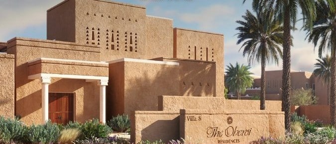 A beautifully designed villa with traditional Najdi architectural elements, featuring earthy tones and surrounded by palm trees and native plants.