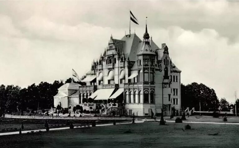 The historic Carl Ziese Villa in Elbląg, Poland, showcasing its tall turrets and intricate details with a flag flying atop.