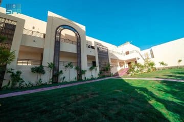 Front view of the new building housing double tents in Mina, surrounded by green landscaping