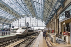 High-speed train arriving at Bordeaux Saint-Jean station beneath a classic iron and glass roof.