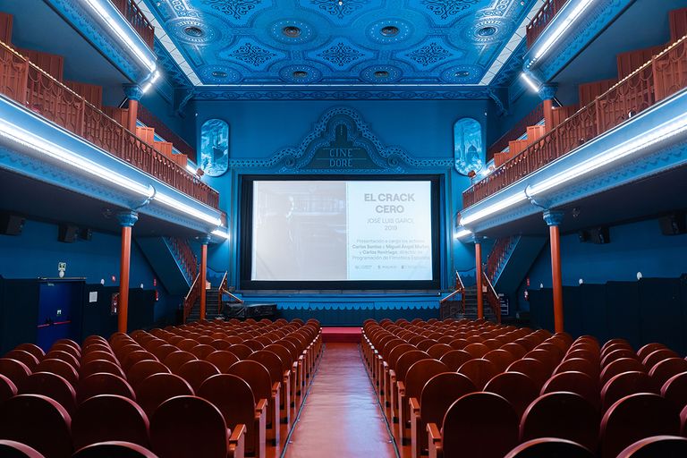 A luxurious cinema hall with Art Nouveau design, featuring wooden columns, blue-decorated balconies, and an ornate ceiling that adds a touch of historical elegance to the space.