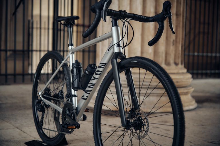A Canyon Endurance: AllRoad bike with a practical design and silver frame, standing against a stone background.