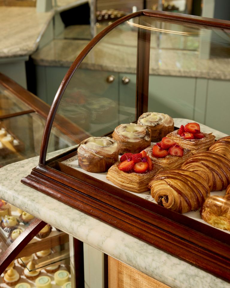 A delightful display of pastries in a glass case, featuring croissants filled with berries, chocolate-covered Napoleons, and other tempting treats.