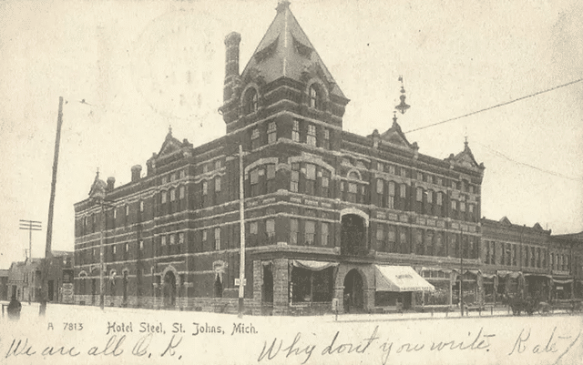 The Steel Hotel in Saint Johns, Michigan, showcasing its elegant late Gothic Revival style with arched windows and a prominent tower, reflecting the beauty of historical architecture.