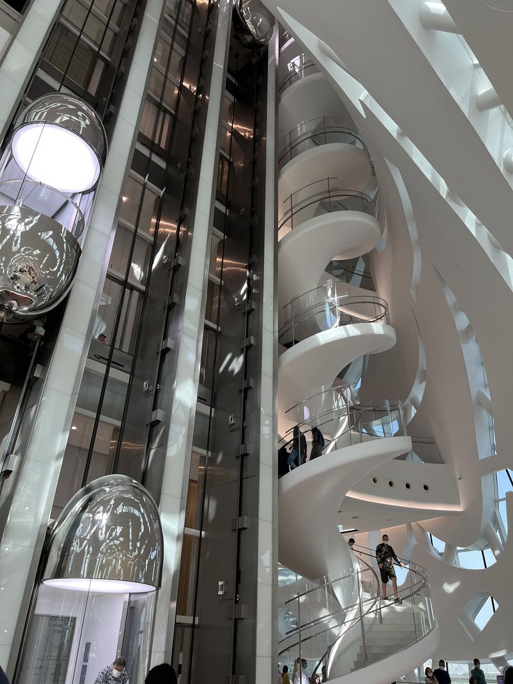 An interior view of the Museum of the Future in Dubai, showcasing a spacious hall with futuristic spiral staircases and walls adorned with elegant Arabic calligraphy, as visitors explore the space.