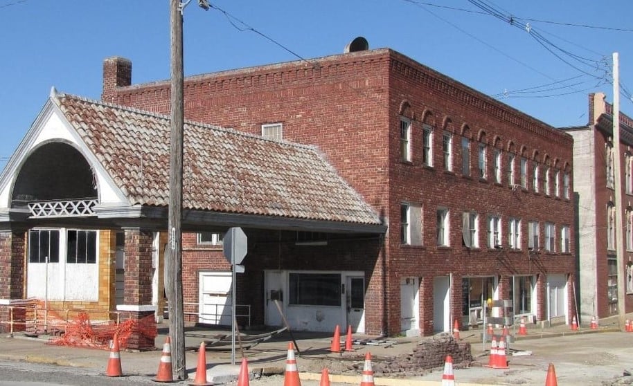 An old brick building undergoing renovations, surrounded by traffic cones and barriers.