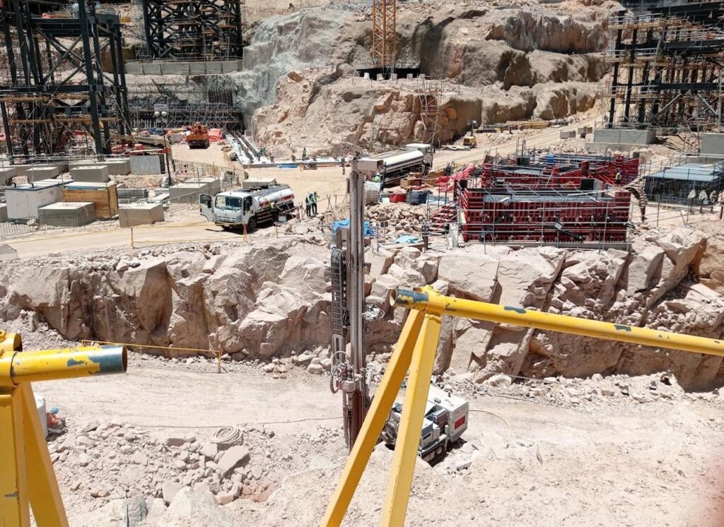 عامل يرتدي زيًا أمان يُعمل على موقع البناء، مع وجود مقاعد وأدوات إنشائية حوله.