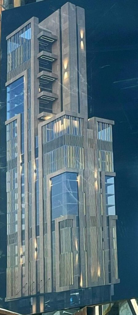 A modern skyscraper with a sleek, geometric design featuring glass panels and warm lighting. The building's sharp lines and structured layout create a futuristic yet inviting architectural presence.