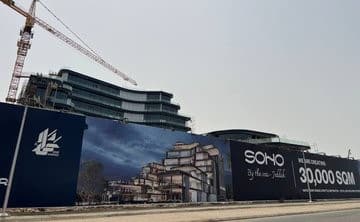 صورة تظهر لافتة كبيرة للمشروع سoho Square في جدة، حيث يُرى اسم المشروع وشعار المطور العقاري. اللافتة تحتوي على معلومات عن المساحة الإجمالية التي تبلغ 30,000 متر مربع، مع وجود كرينات عملاقة في الخلفية تشير إلى التقدم في العمل.
