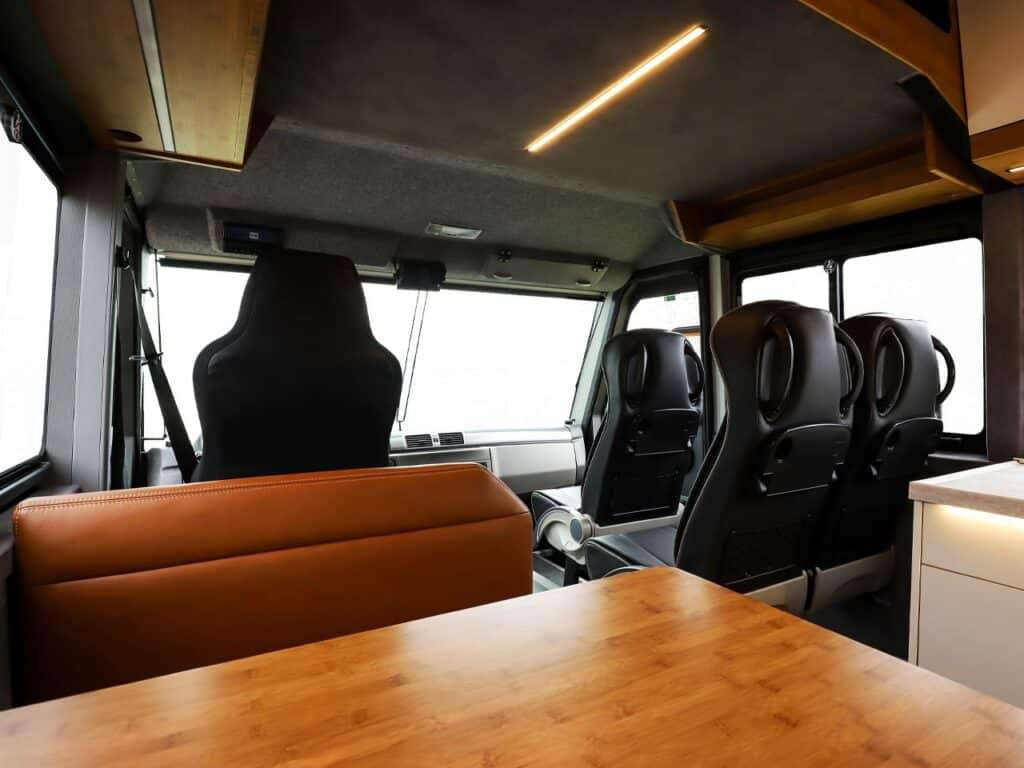 Leather seats in the Torsus Liberra bus, with a wooden table in front for working or dining, and large windows providing clear views of the road ahead.