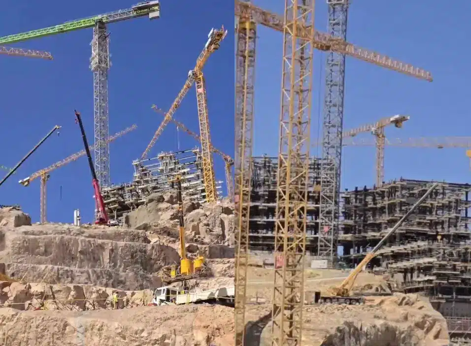 A large construction site in the desert featuring massive cranes working on a tall building.