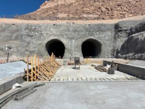 The entrance of the under-construction mountain tunnel with ongoing construction work around it.
