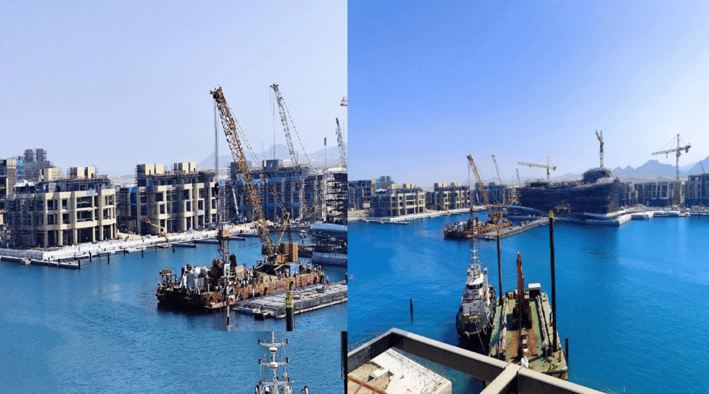 A collage of two images capturing the dynamic construction activity at Amaala, a luxury destination on Saudi Arabia&rsquo;s Red Sea coast. The first image shows a bustling waterfront scene with multiple buildings under development, surrounded by scaffolding and cranes. Tower cranes dominate the skyline, indicating active progress in building modern structures. The second image provides a broader view of the area, showcasing a marina with clear blue waters, floating barges, and ongoing construction projects. The serene sea contrasts beautifully with the industrial elements of the site, highlighting the blend of development and natural beauty.