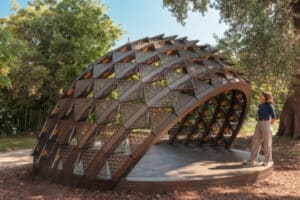 The exterior view of the SOMBRA Pavilion featuring the metal rib structure and perforated panels that form the sustainable passive shading system at the Time Space Existence exhibition.