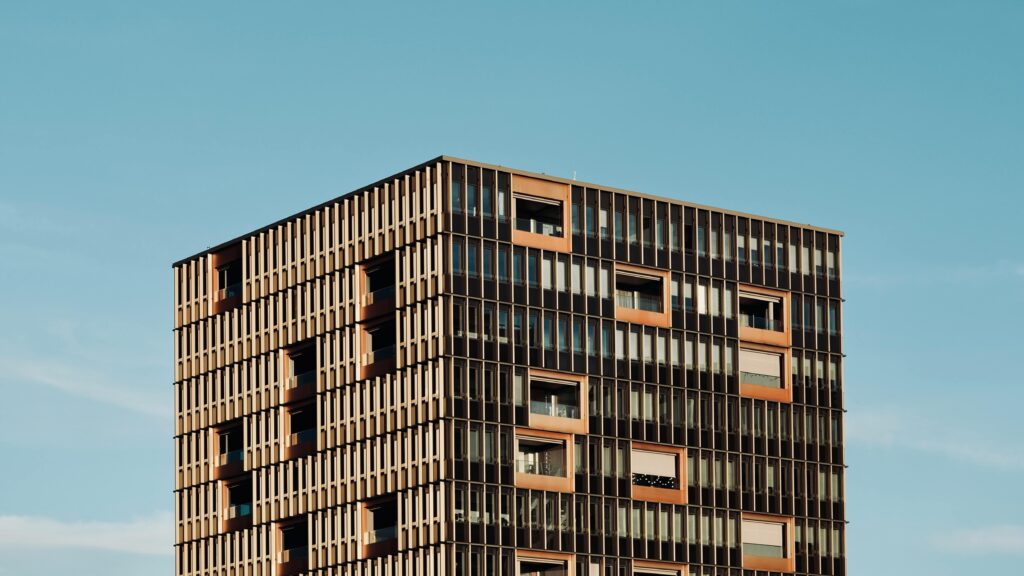 واجهة مبنى حديث تعتمد هيكلًا معدنيًا شبكيًا يعكس الضوء ويخلق نمطًا هندسيًا بديعًا.