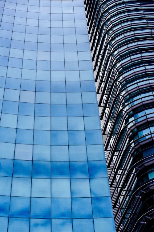 واجهة ناطحة سحاب زجاجية حديثة تعكس السماء وتُبرز خطوطها الهندسية.