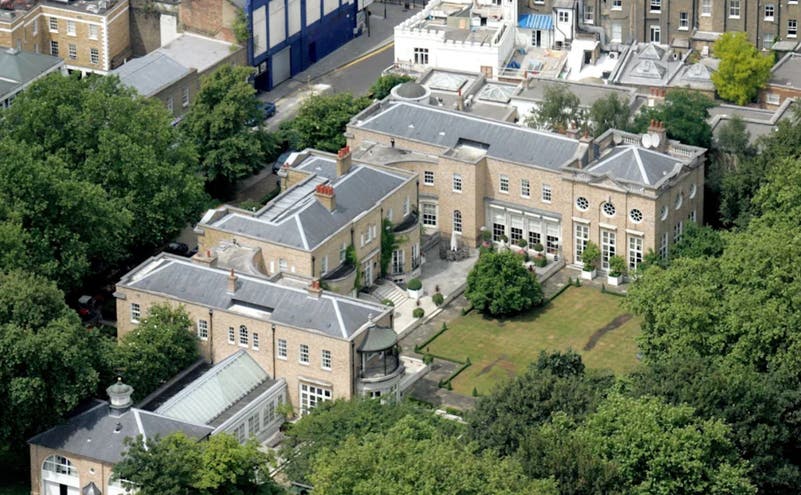 صورة جوية لقصر كبير في منطقة سكنية راقية تحيط به الأشجار والمباني الفاخرة