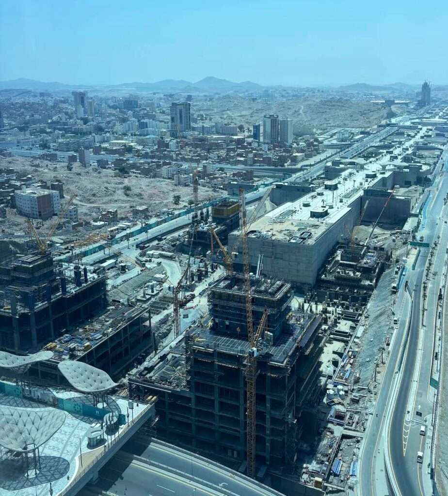 Aerial view of the Wajhat Makkah project site in Makkah showing tower construction and infrastructure progress along King Abdulaziz Road.