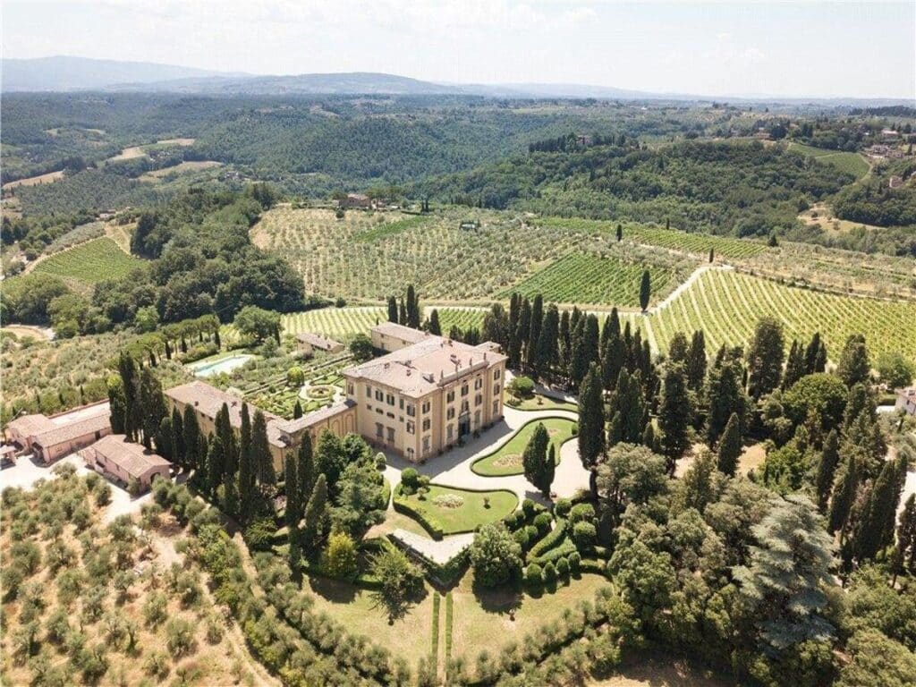 فيلا نهضوية تقليدية تحيط بها أشجار السرو والتلال التوسكانية الخضراء.