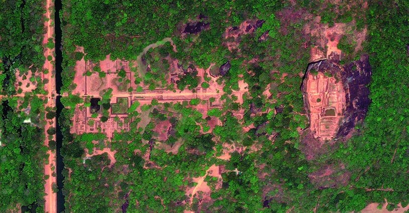 Aerial view showcasing the symmetrical square water gardens at the base of Sigiriya Rock, surrounded by forest.