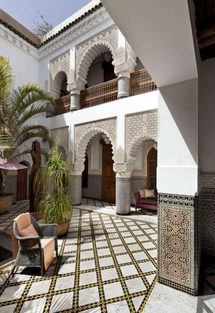 Interior courtyard of a Moroccan riad with arched columns and traditional zellij under soft natural light.