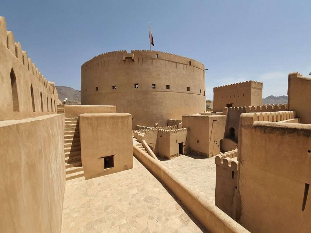 The massive round tower of Nizwa Fort beneath a clear sky