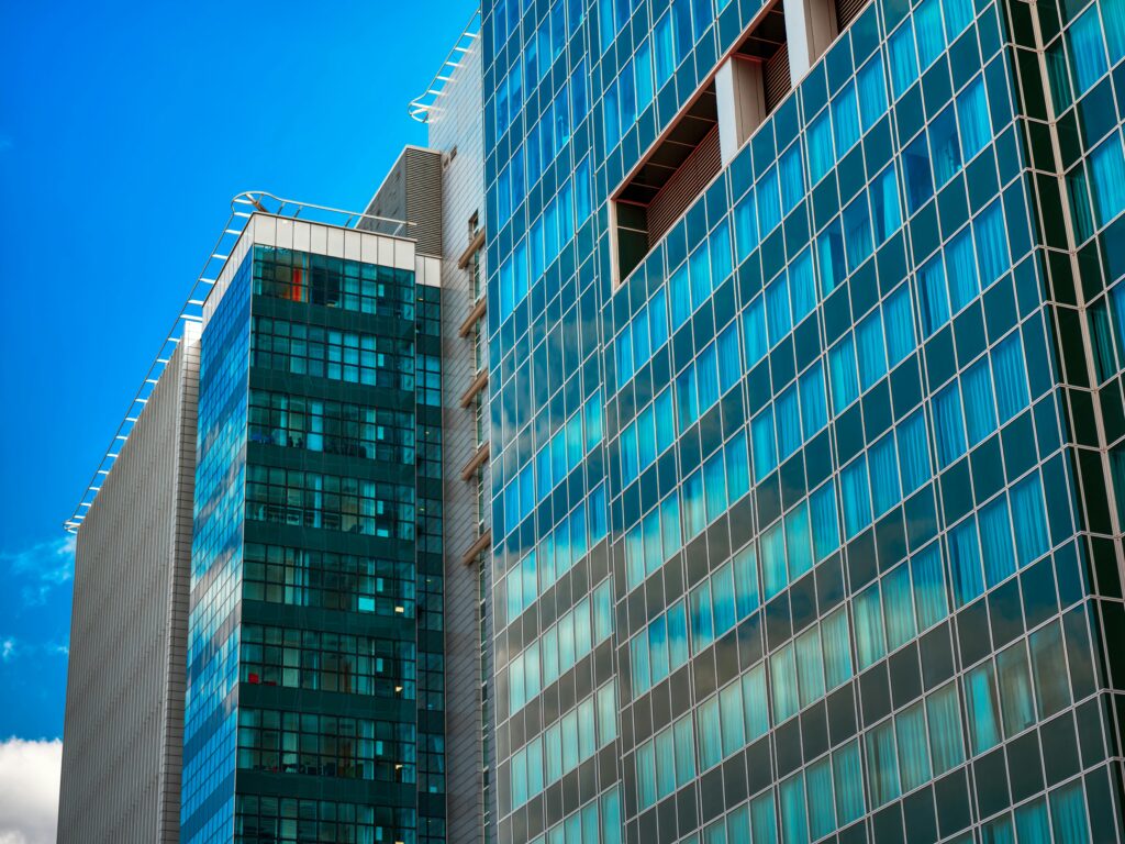 Vertical detail of a glass facade with a grid pattern reflecting the urban environment