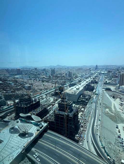 On-site photo from the Wajhat Makkah project showing active tower construction and infrastructure development alongside the highway.