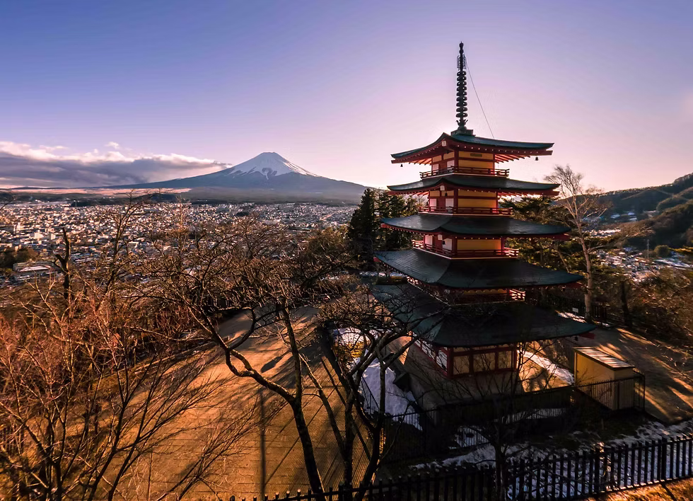 Japanese wooden pagoda rising among trees and mountains at sunset