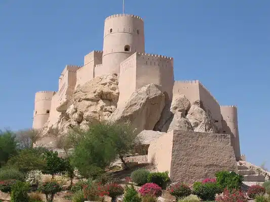Bahla Fort lit up at sunset, showcasing its traditional mud-brick walls