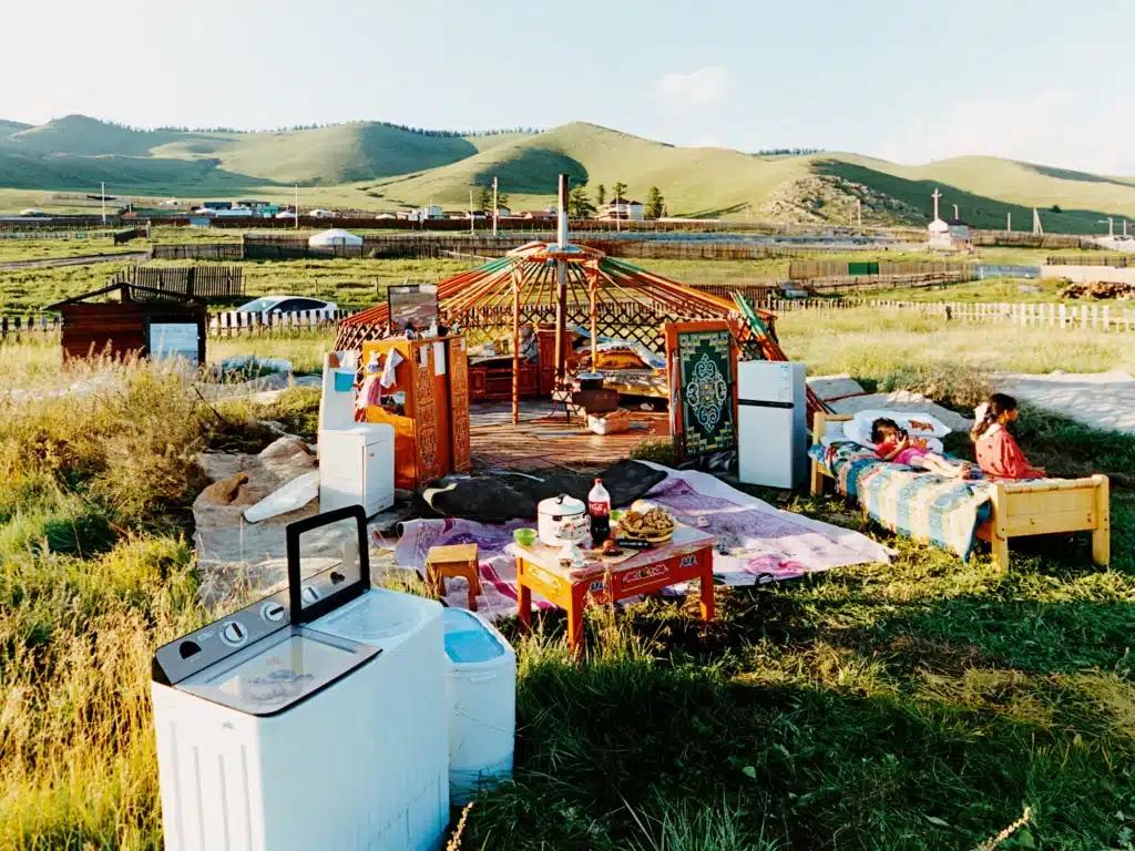A Mongolian nomadic family assembling a yurt outdoors as part of their mobile lifestyle.