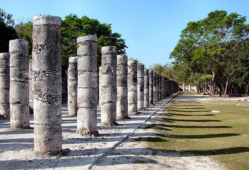 A courtyard surrounded by stone pillars, reflecting Mayan religious rituals and military structure