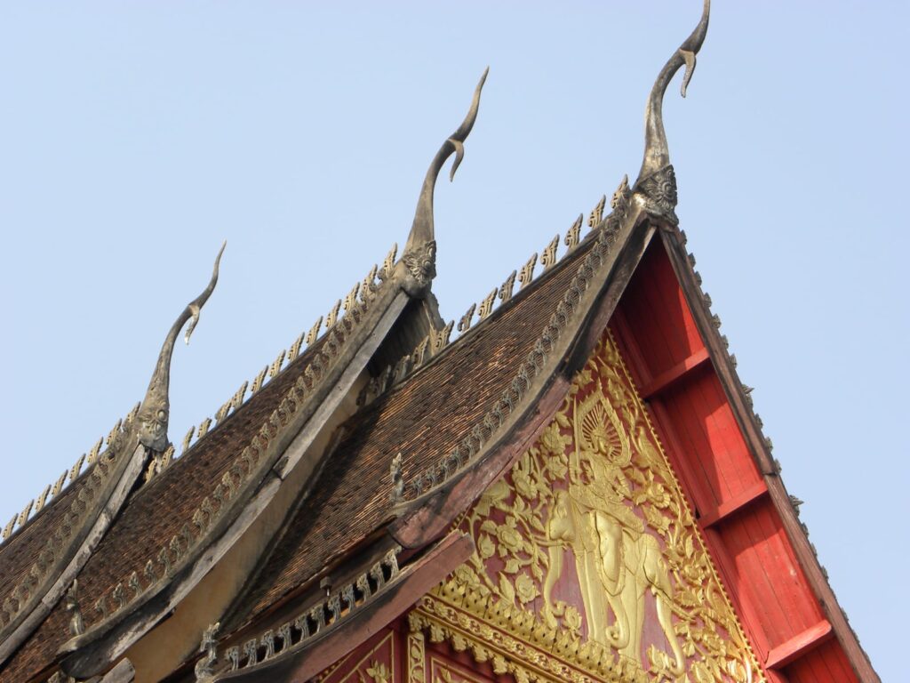 لقطة قريبة لسقف معبد تايلاندي بزوايا مرتفعة ونهايات مدببة على الطراز التقليدي.