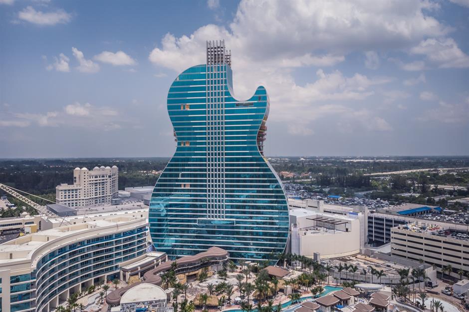 A photo of a massive guitar-shaped hotel illuminated with vibrant lights at night, showcasing a unique fusion of architecture and music.