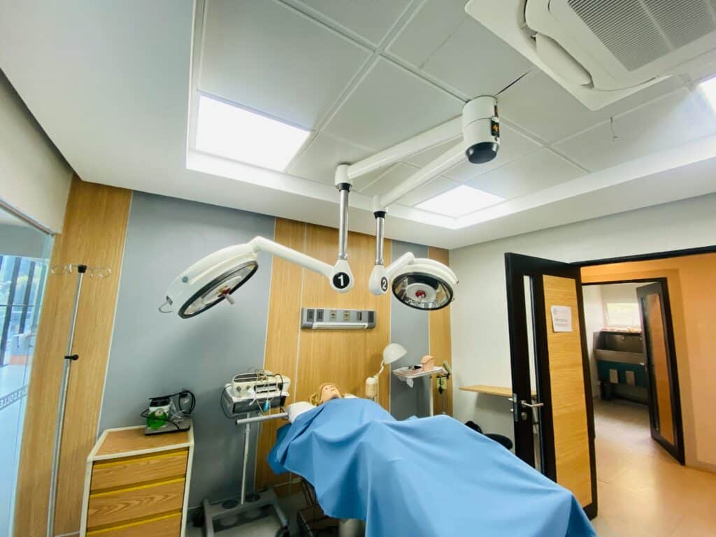 A mannequin placed on an operating table inside a medical room simulating a surgical training environment.