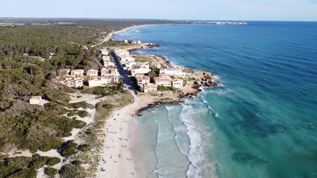 A stunning aerial view of Ses Covetes beach and coastline in Mallorca, showcasing serene turquoise waters and sandy shores.