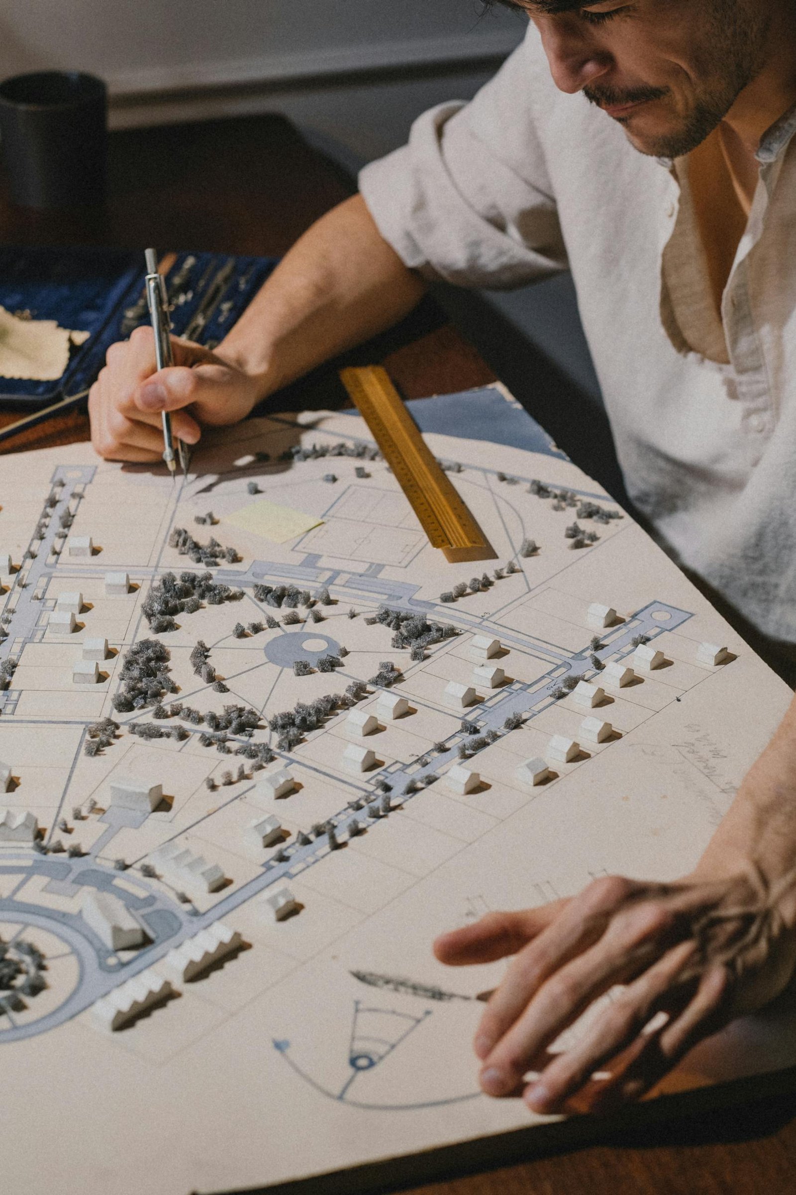 Architect working on a detailed landscape model at a desk.