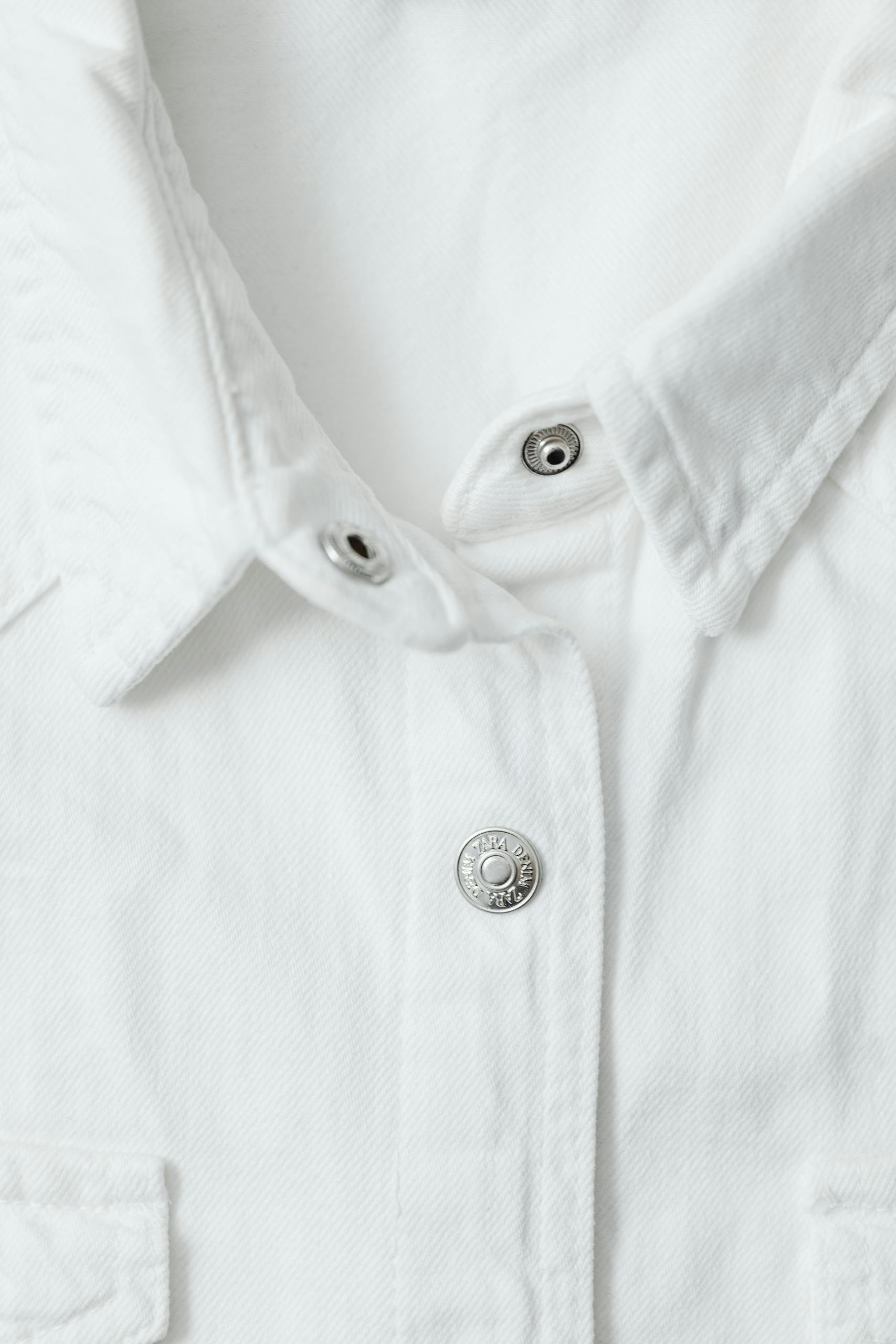 Detailed view of a white shirt's buttoned collar showcasing fabric texture.
