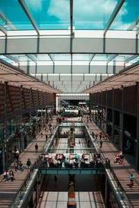 Explore the bustling atmosphere and sleek design of Germiston's modern shopping mall with natural light and glass panels.