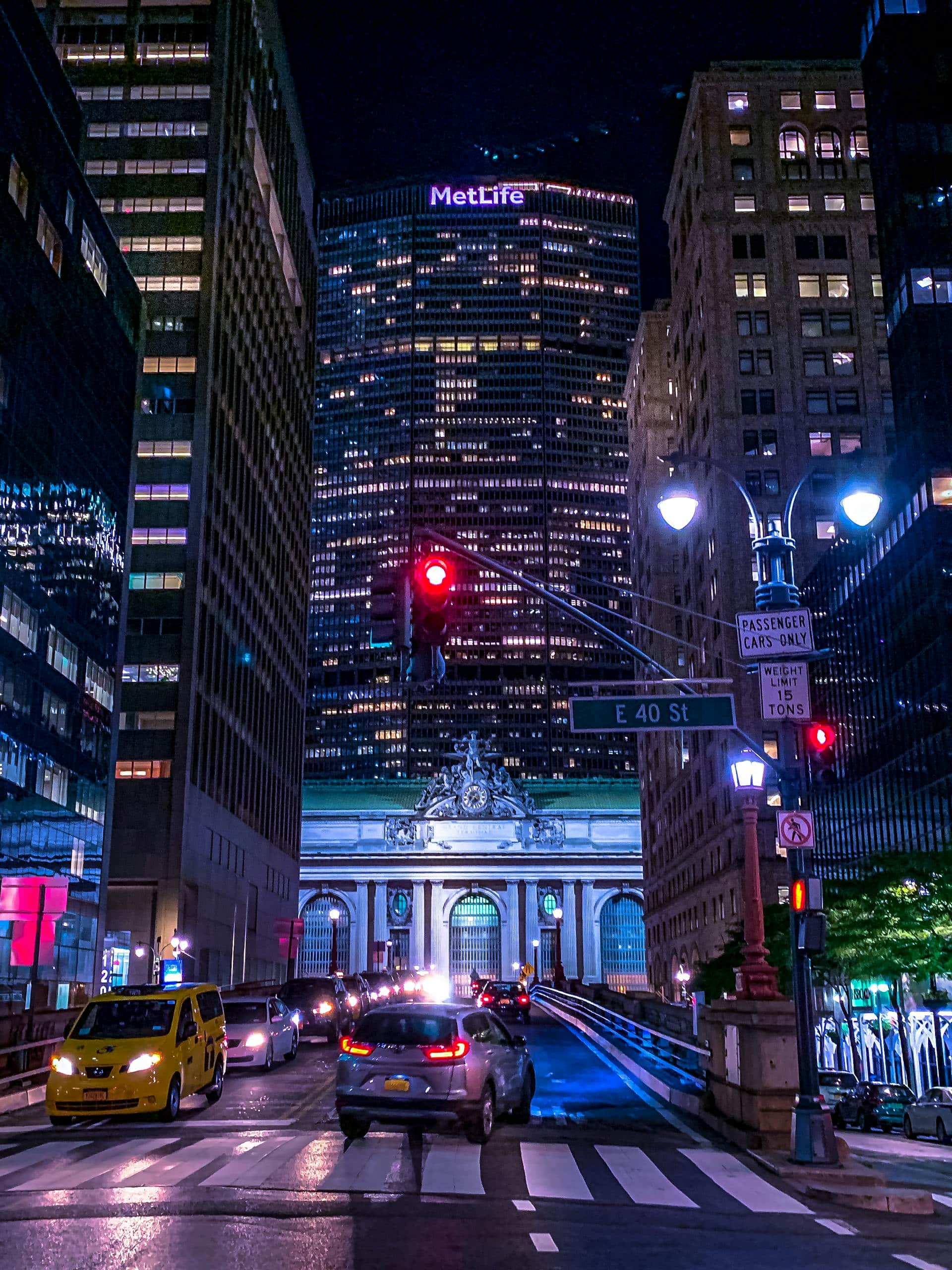 Night view of New York City traffic near Grand Central Terminal, with MetLife Building in the background.