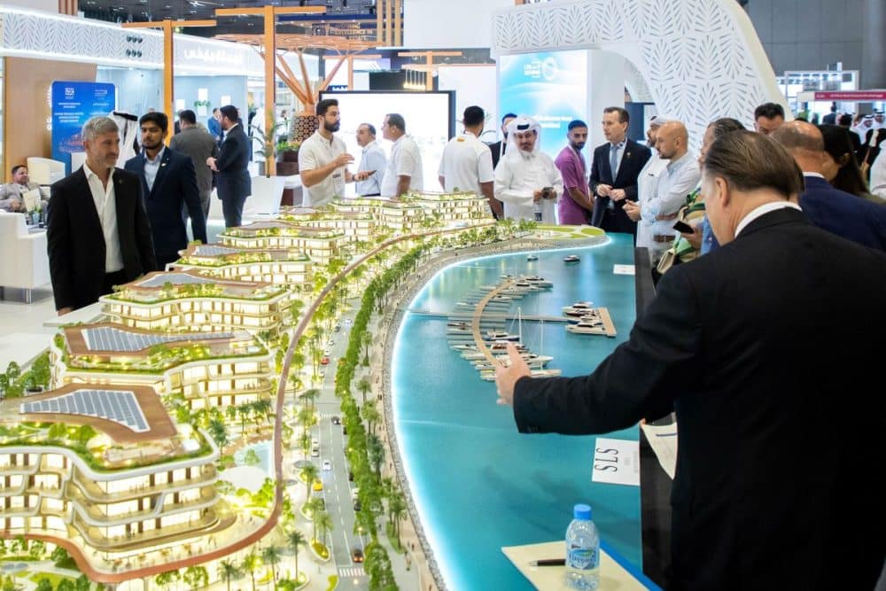 Visitors exploring a waterfront architectural model at Cityscape Qatar 2025